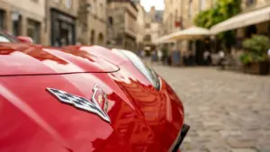 Punane Chevrolet Corvette sportauto esiosa koos embleemiga ajaloolisel munakivitänaval vanalinnas.