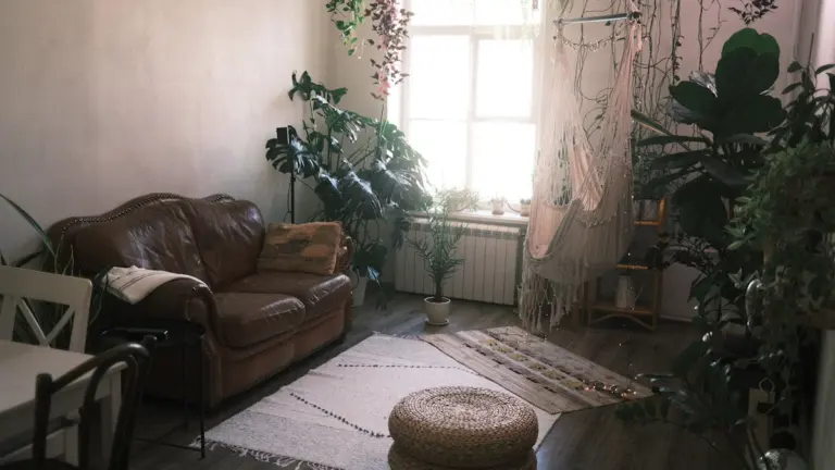 Hubane elutuba rohkete toataimede ja mugava pruuni nahkdiivaniga, mis loob rahuliku atmosfääri.