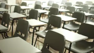 Klassiruum tühjade laudade ja toolidega tähistab õpilaste privaatsuse ja koolikontrolli teemat.