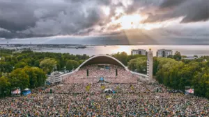 Linnulennuline vaade Tallinna lauluväljakule, kus suur rahvamass on kogunenud laulupeo kontserdile päikeseloojangul.