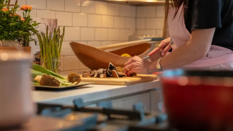 Naine valmistab koduses köögis tervislikke toite, lõigates värskeid köögivilju puidust lõikelaual.