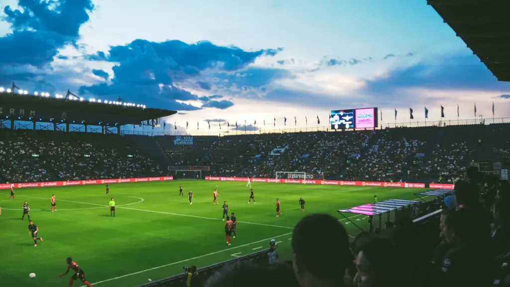 Jalgpallimäng Pärnu Rannastaadionil õhtuhämaruses, tribüünid on täis kaasaelavaid pealtvaatajaid.