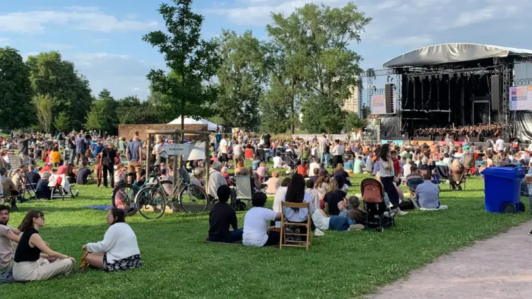 Inimesed istuvad murul vabaõhukontserdil, oodates suvist sünnipäeva kontserti kultuurikeskuse juures.