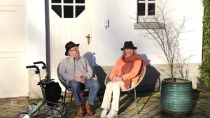 Eakas paar istumas päikeselisel päeval Mehikoorma seltsikeskuse sarnasel õuealal puhkamas.