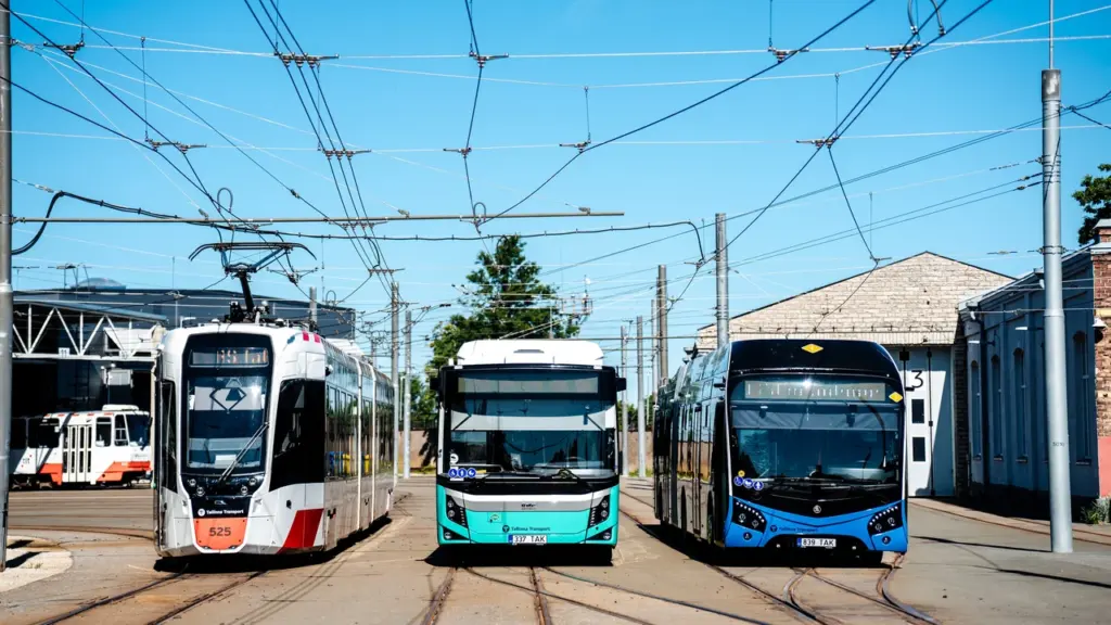 Tramm ja kaks linnaliinibussi seisavad kõrvuti Tallinna ühistranspordi depoo territooriumil päikeselisel päeval.