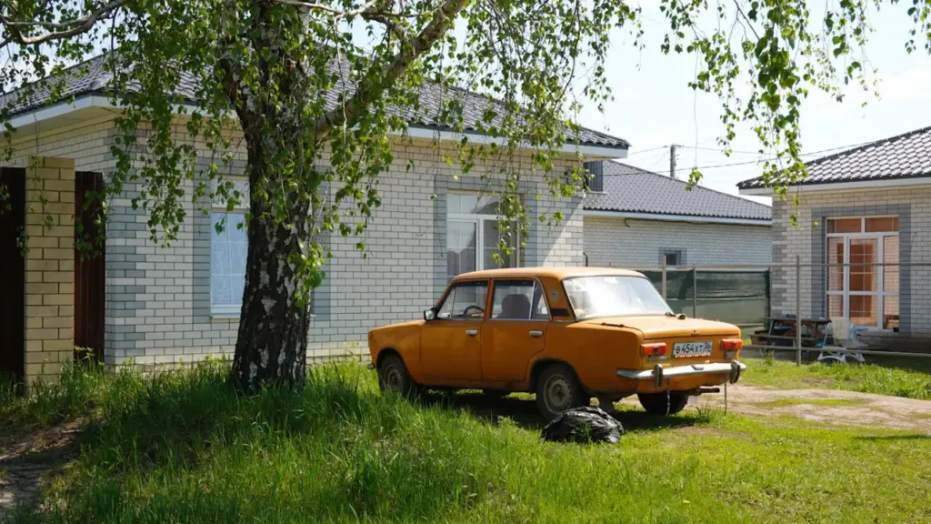 Oranž retroauto pargitud maamaja ees päikeselisel suvepäeval Eestis.